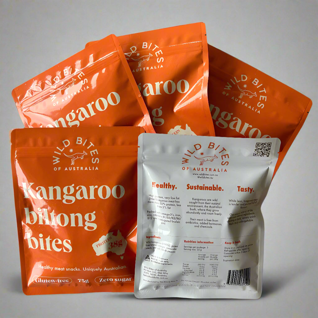 Multiple orange and white pouches of kangaroo biltong bites, with the packaging text indicating the product is healthy, sustainable, and tasty, along with the brand 'Wild Bites of Australia'.